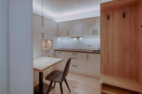 een keuken met witte kasten en een tafel en een stoel bij ADAM Suites - Brixen Card included in Bressanone