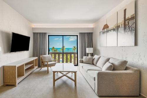een woonkamer met een bank en een tv bij Fiesta Americana Cancun Villas in Cancun