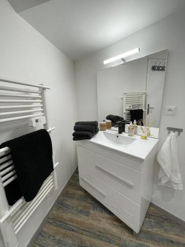 un bagno bianco con lavandino e specchio di La détente a Lézignan-Corbières