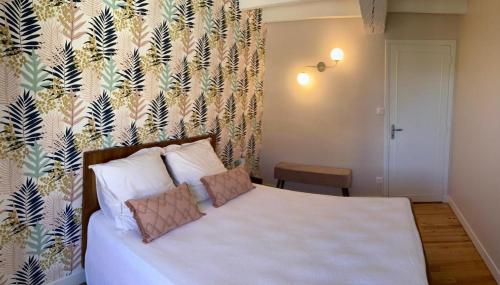 een slaapkamer met een wit bed met bloemenbehang bij Chez denise in Paulinet