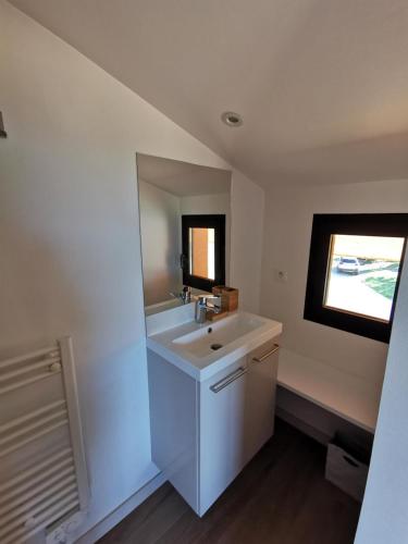 une salle de bains blanche avec un lavabo et une fenêtre dans l'établissement Eucalyptus, à Thuir