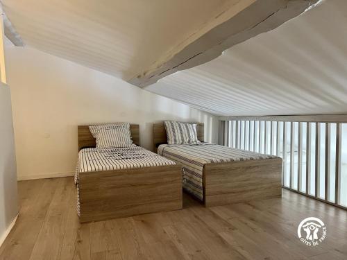 - 2 lits dans une chambre dotée de parquet et de fenêtres dans l'établissement Sous les toits, à Canet d'Aude