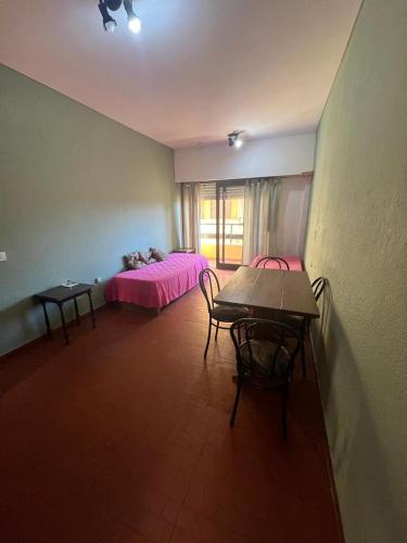 a room with a table and a bed with pink sheets at Miramar 19 in Miramar