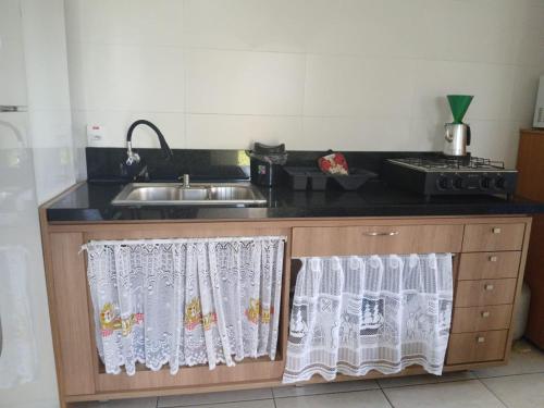a kitchen with a sink and a counter with curtains at Residencial Daitx in Capão da Canoa