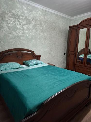 a bedroom with a bed with a green comforter at Baleni Agritourism Guesthouse in Gyulagarak