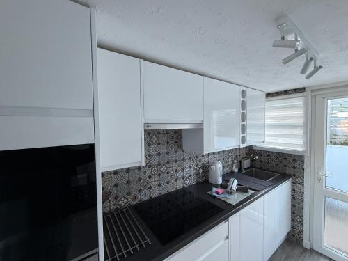 a kitchen with white cabinets and a black counter top at 92 Blueberry Lodge - Sea Views in Westward Ho