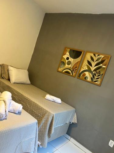 Cette chambre comprend 2 lits et 2 photos sur le mur. dans l'établissement Linhares beach, à Cabedelo