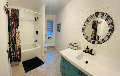 ein Badezimmer mit Waschbecken, Spiegel und Badewanne in der Unterkunft Chalet -Havre au bord de l'eau in Chertsey