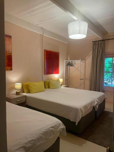 a bedroom with two beds and a chandelier at Villa Olivia in Riebeek-Kasteel