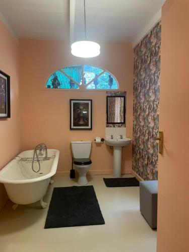 a bathroom with a tub and a toilet and a sink at Villa Olivia in Riebeek-Kasteel