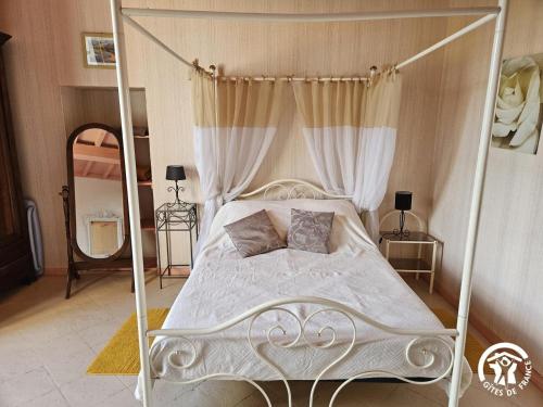 a bedroom with a white canopy bed with two pillows at Roumanieu le gite in Saint-Gauzens