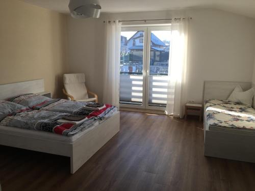 ein Schlafzimmer mit einem Bett, einem Stuhl und einem Fenster in der Unterkunft Apartmány Zuberec 893 in Zuberec
