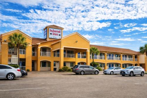 a hotel with cars parked in a parking lot at Island Inn By OYO Galveston Beach, TX in Galveston