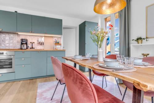 a kitchen with a wooden table and pink chairs at Haus am Seeufer mit Badestelle in 200m, große Sonnenterrasse, umzäunter Garten, Hunde willkommen in Rheinsberg