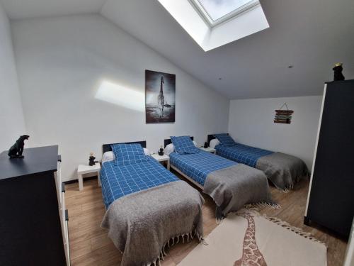 a bedroom with three beds with blue sheets and a skylight at Gite Bergamote in Champenoux
