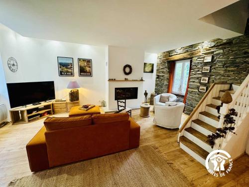 een woonkamer met een bank en een stenen muur bij Le moulin de cameliere in Caudebronde