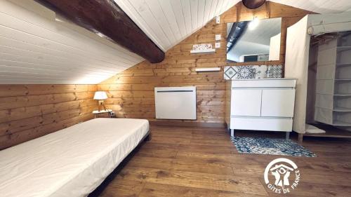 een slaapkamer met een bed in een kamer met houten wanden bij Le moulin de cameliere in Caudebronde