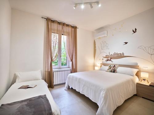 a white bedroom with two beds and a window at Domus Pallium in Siena