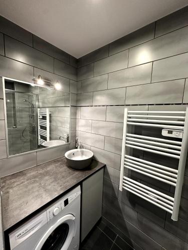 a bathroom with a sink and a washing machine at Appartement - Le Prestige in Saint-Chéron