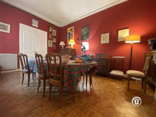 een eetkamer met een tafel en stoelen en rode muren bij La maison bachelet in Claira