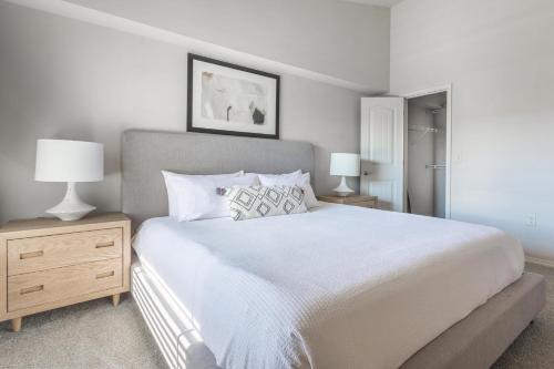 een slaapkamer met een groot wit bed en twee lampen bij Landing Stylish 1BD Courtyard Pool in Broken Arrow