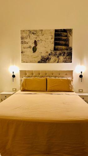 a bedroom with a bed with yellow sheets and a painting at Ada&niní in Galatina