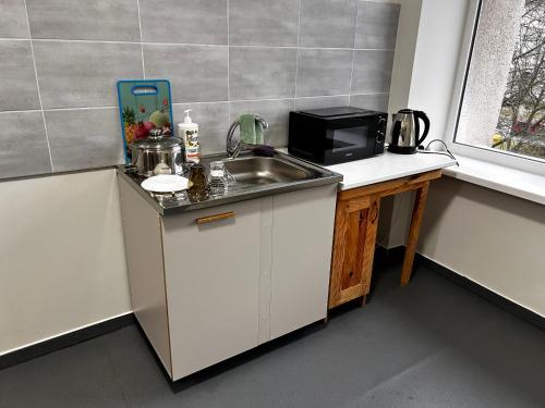 een keuken met een spoelbak en een magnetron bij ЛофтХостел in Novoyavorivsk