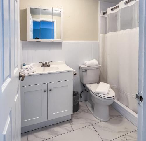 a white bathroom with a toilet and a sink at Ocean Lodge in Boca Raton