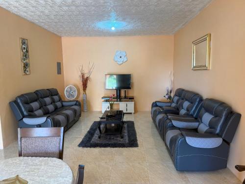 un soggiorno con divani in pelle nera e TV di Glenmuir Villa a May Pen