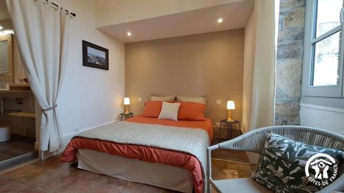 een kleine slaapkamer met een bed en een stoel bij L'oree de la gresigne in Cordes-sur-Ciel