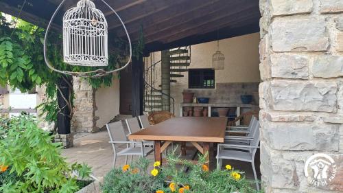 een houten tafel en stoelen op een terras met een vogelkooi bij L'oree de la gresigne in Cordes-sur-Ciel