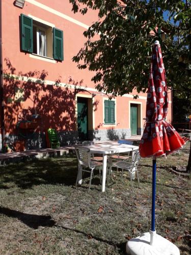a table and a red umbrella in front of a building at Villa Bella bed and breakfast in Favale di Malvaro