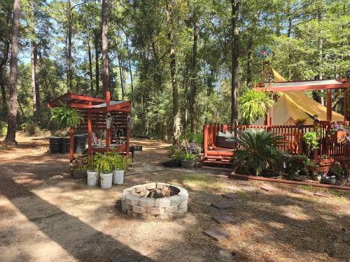 a backyard with a fire pit and a tent and trees at Paradise Gardens Glamping in Westville