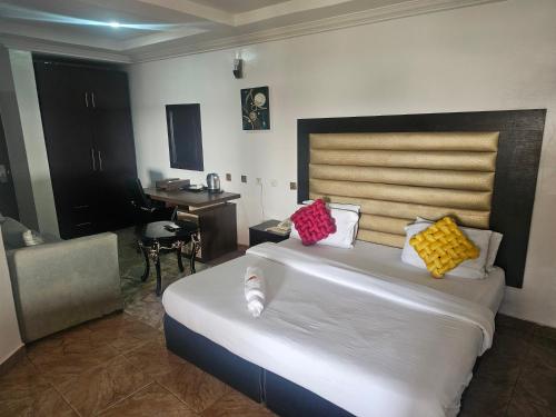 ein Schlafzimmer mit einem großen weißen Bett mit bunten Kissen in der Unterkunft GRAND PARK HOTEL AND SUITEs in Egbe