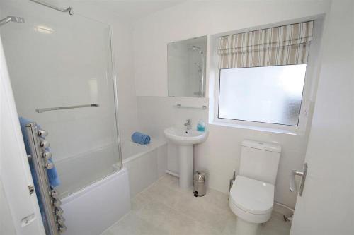 a white bathroom with a toilet and a sink at 3 Bed in Gower oc-hh2105 in Rhossili