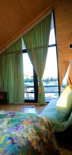 a bedroom with a bed and large windows at Our village in Khoni