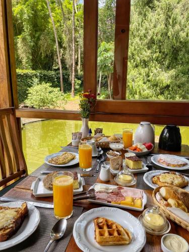 a table filled with breakfast foods and orange juice at Pousada Tucano Do Cuiabá in Itaipava