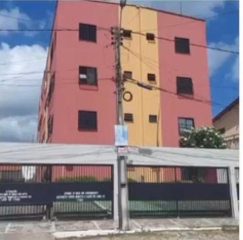 een roze gebouw met een hek ervoor bij Apto Mobiliado próximo à praia in Caucaia