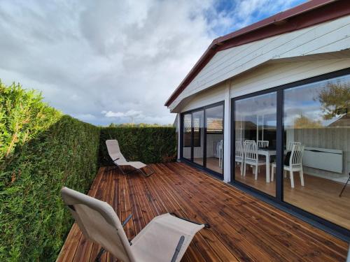 une terrasse en bois avec des chaises blanches et une table dans l'établissement Chalet 6 pers à 10km de Cabourg, à Dozulé