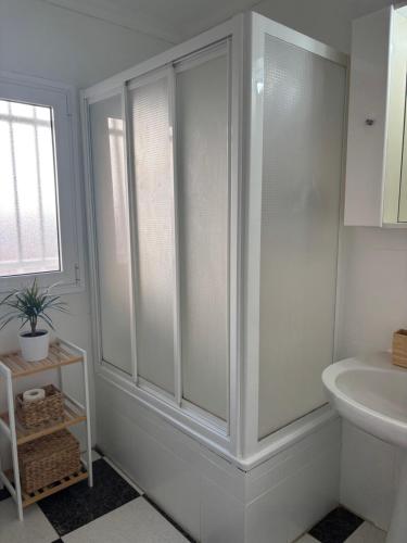 een witte badkamer met douche en wastafel bij Apartamento Clavel in Chipiona