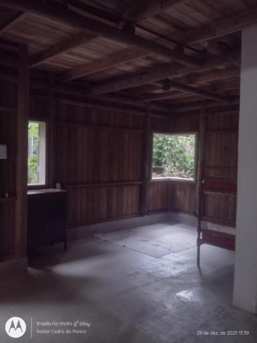 een lege kamer met houten lambrisering en twee ramen bij Hostel Cedro do Ronca in Paraty