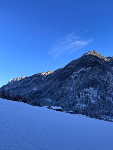 a house in the snow next to a mountain at Bergkraft in Assling