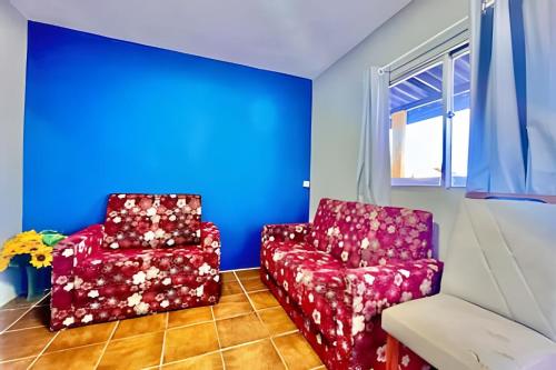 a living room with a red chair and a red chair at Quarto em Matinhos | Viva o Melhor do Litoral in Matinhos