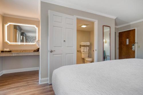 a white bedroom with a bed and a bathroom at Best Western Plus French Quarter Courtyard Hotel in New Orleans