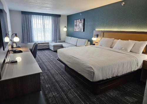 una camera d'albergo con un letto grande e un divano di La Quinta Inn & Suites by Wyndham Minot a Minot