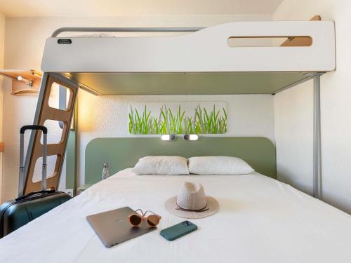 a bedroom with a bed with a hat and a suitcase at ibis budget Strasbourg Sud Illkirch in Geispolsheim