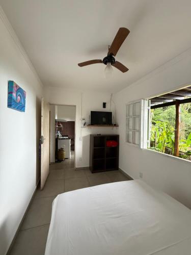 een slaapkamer met een bed en een plafondventilator bij Suites do Félix in Ubatuba