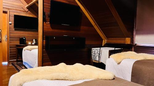 a room with three beds and a flat screen tv at DOM Hotel in Campos do Jordão