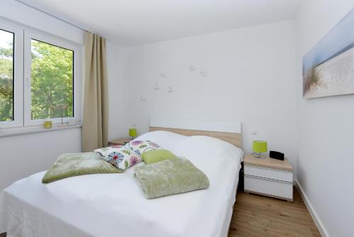 una camera da letto con un letto bianco con due cuscini sopra di Ferienwohnung Sonnensegler a Juliusruh