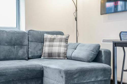 a blue couch with a plaid pillow on it at 2Bed Apt in City Centre With Free parking Sleeps 9 in Nottingham